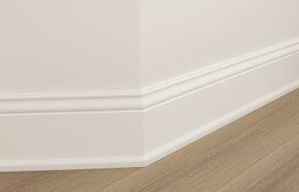 Detalle de molduras de madera instaladas entre muro y piso laminado en un espacio interior